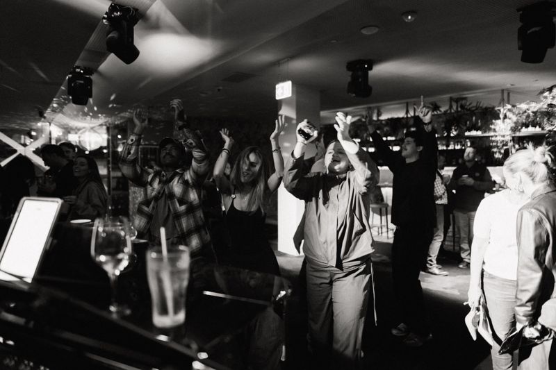 Black and white: crowd dancing with hands up under the lights
