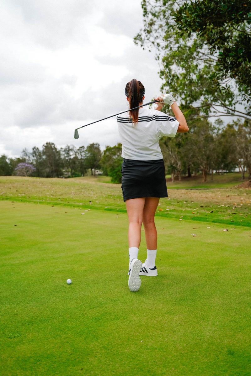 Golfer mid-swing on the green, shot from behind