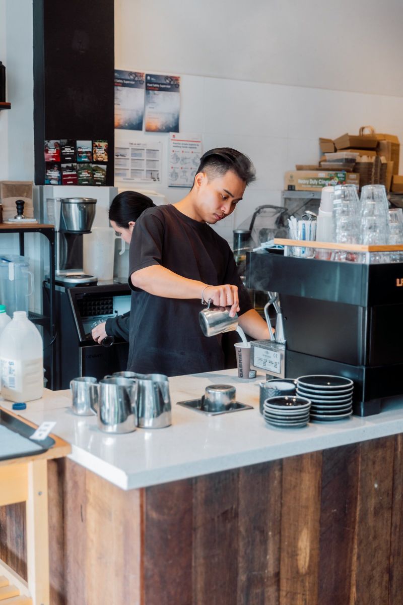 Barista pouring a takeaway coffee at the machine
